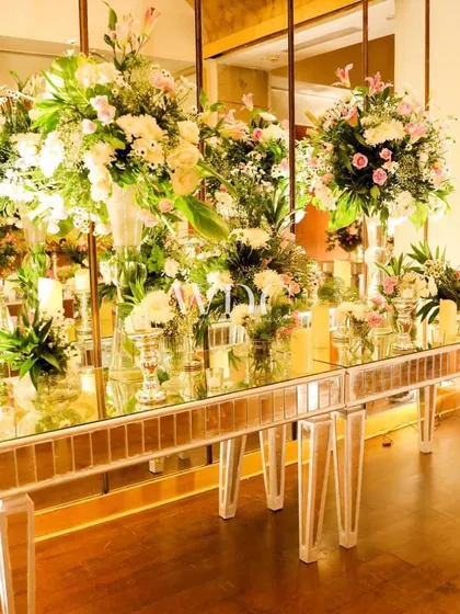 A beautiful console table with a mirrored front, adorned with an abundance of pastel and white flowers, reflecting the light and adding to the room's vintage charm.