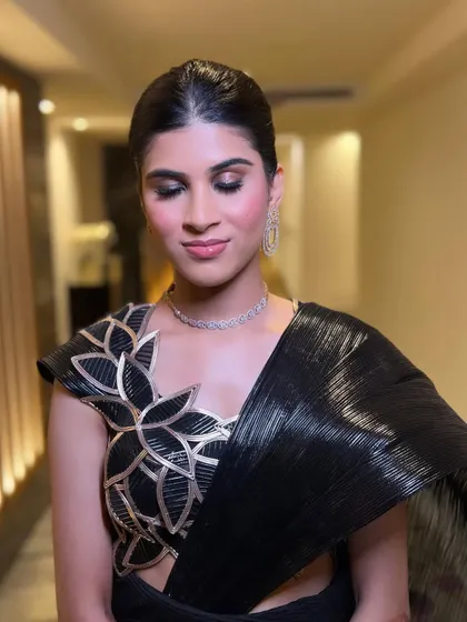 A dewy makeup look with glossy lips for a Bollywood themed night. The skin is fresh and luminous, paired with a classic sleek bun for a touch of elegance.