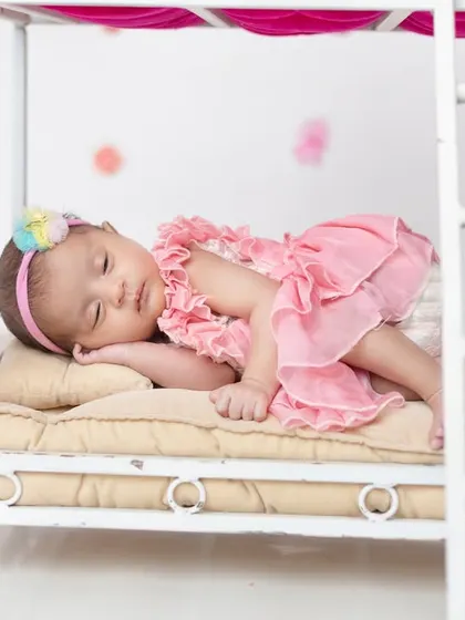 A close-up of one of the twins sleeping peacefully on the bottom bunk of the miniature bed prop.