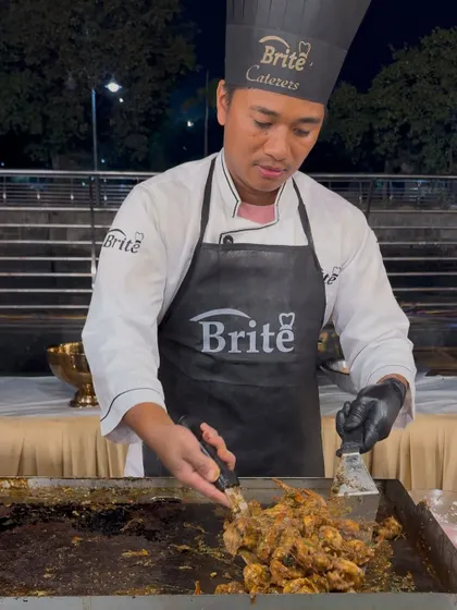 A chef expertly stir-frying Prawns Teppanyaki on a flat-top grill.