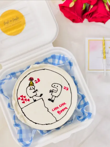 A fun and quirky bento cake with a custom "Chk Chk Boom" message and a unique stick-figure drawing, perfect for celebrating a personal milestone.