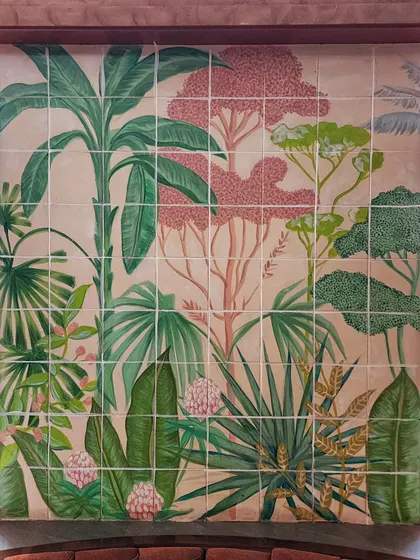 A detailed shot of one of the hand-painted tile panels at The Koha. Each tile is part of a larger picture, coming together to form a lush scene of palm trees, tropical plants, and flowers.