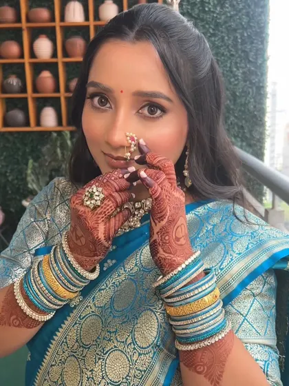 A playful and happy moment, with the bride adjusting her nath. The makeup is fresh and luminous, perfect for a daytime engagement ceremony.