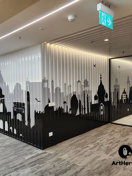 A corner view of the metal shed cityscape mural, showing how the design wraps around the wall. This piece depicts the skyline of Rome, including the Colosseum, adding a global touch to the office.