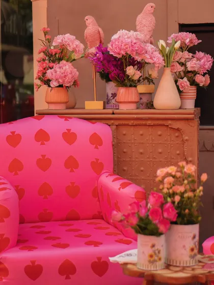 A bold, heart-print armchair in hot pink, surrounded by more floral arrangements and porcelain parrots, creating a whimsical and romantic seating nook.