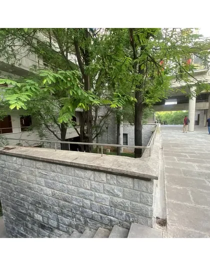 We retained existing trees within the new hostel's courtyards. The stone retaining walls and paved walkways create usable outdoor spaces that respect the natural topography of the site.
