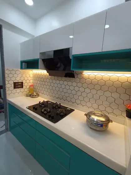 We love adding a pop of color. This modular kitchen features a refreshing teal and white color scheme, complemented by a modern hexagonal tile backsplash and warm under-cabinet lighting.