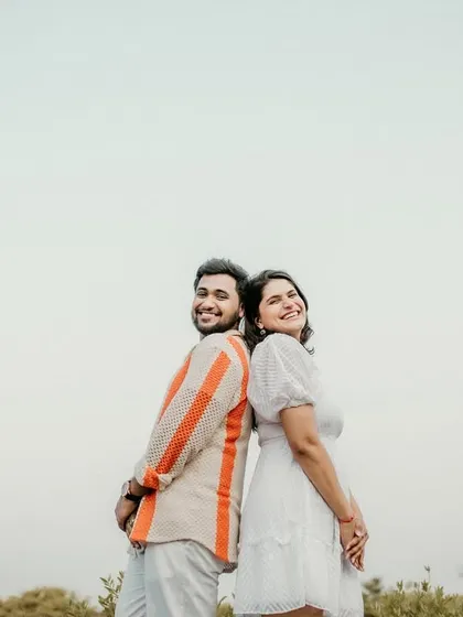 A fun, back-to-back pose against the open sky. This minimalist shot highlights the couple's happy expressions and carefree attitude.