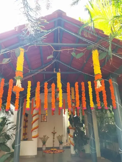 An entrance to a covered outdoor space decorated with hanging marigold garlands, setting a festive and traditional tone for a Haldi or Mehendi ceremony.