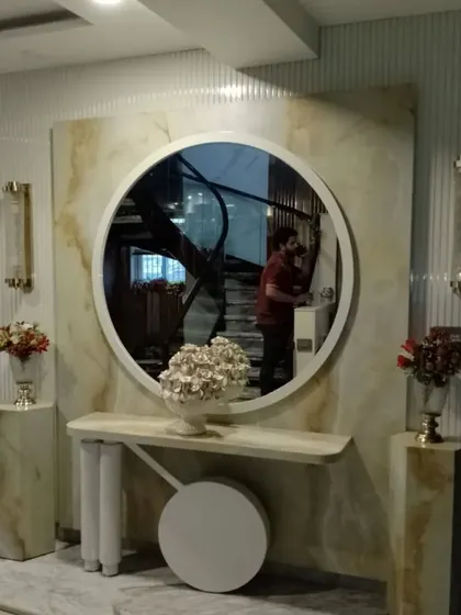 A luxurious foyer design featuring a statement marble console area. The large round mirror, onyx marble pedestals, and elegant wall sconces create a grand and welcoming entrance.