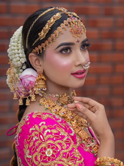 A detailed close-up of the side profile, highlighting the hair accessories, jhumkas, and layered necklaces.