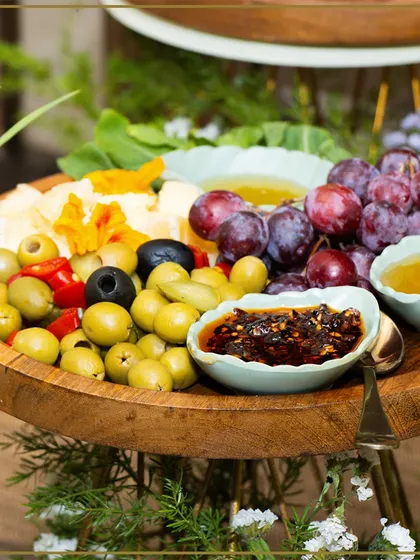 A fresh and colorful platter of green and black olives, grapes, and assorted dips. We use the freshest ingredients to create our vibrant and healthy Mediterranean-inspired boards.