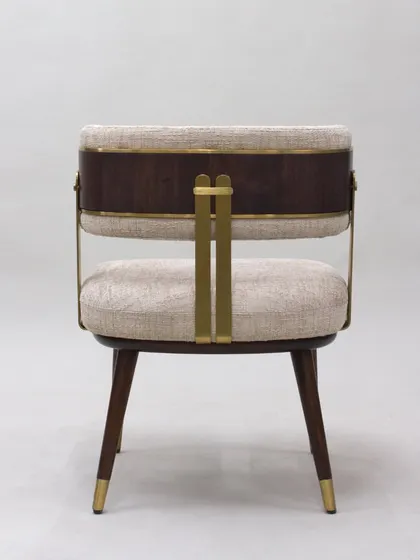 The back of the chair showcases the beautiful interplay between the dark wood frame, the brass metal accents, and the light-colored fabric.