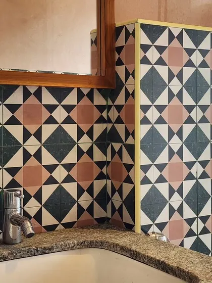 This bathroom features bold, geometric cement tiles in a striking color combination. The simple chrome fixtures and granite countertop allow the tilework to be the main focus of the design.