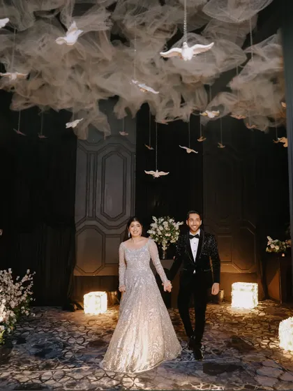 The grand entrance is a cinematic moment, and I capture it with the drama it deserves. Here, the couple makes their way into the reception under a stunning ceiling installation of white doves, setting a magical tone for the evening.