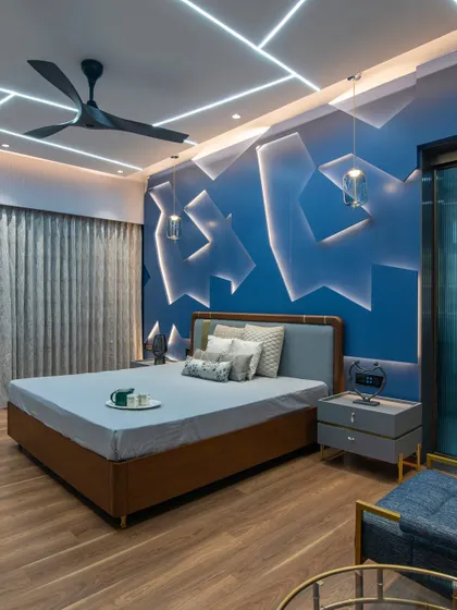 A full view of the blue feature wall, balanced by warm wood flooring and furniture with brass accents. The geometric LED light strips on the ceiling add another layer of modern design.