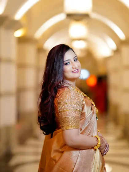 A beautiful portrait of the bride looking back over her shoulder with a warm smile. The shallow depth of field makes her stand out against the softly lit background.