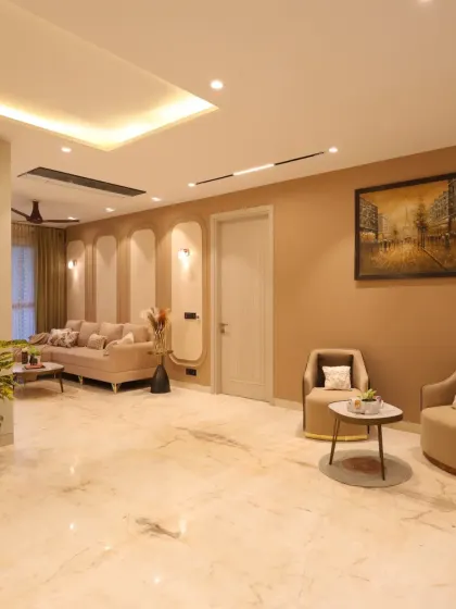 This serene family lounge in Delhi's Harmony House features a soothing beige and brown color palette with intricate wall moldings for a touch of classic elegance.
