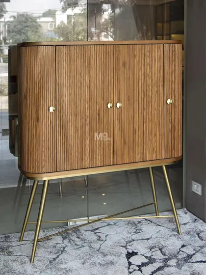 The Ibis bar cabinet blends a rich brown wood finish with sleek metal legs for a timeless appeal. Its fluted doors and curved silhouette make it a standout piece for any contemporary entertainment space.