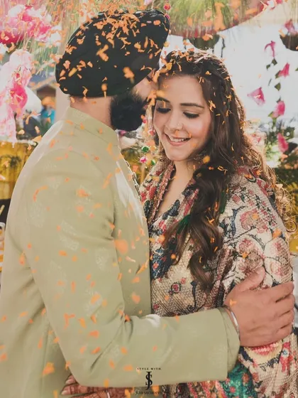 A candid moment of joy and love, showered in flower petals. Their coordinated outfits, a printed kaftan for her and a soft green kurta for him, were perfect for the relaxed vibe of the Mehendi.