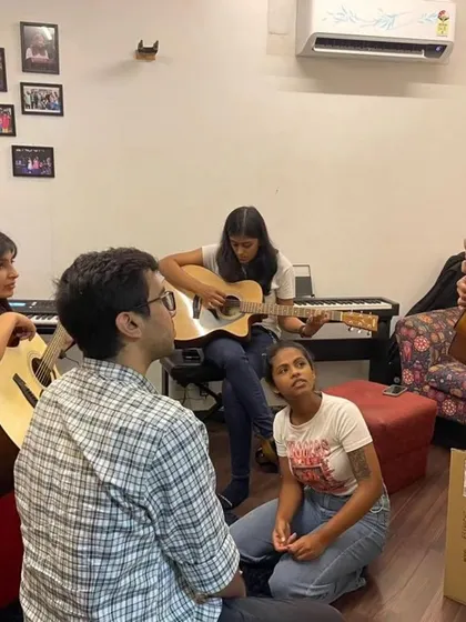 A group of participants learning chords on the guitar. The camaraderie and shared learning experience make our workshops special.