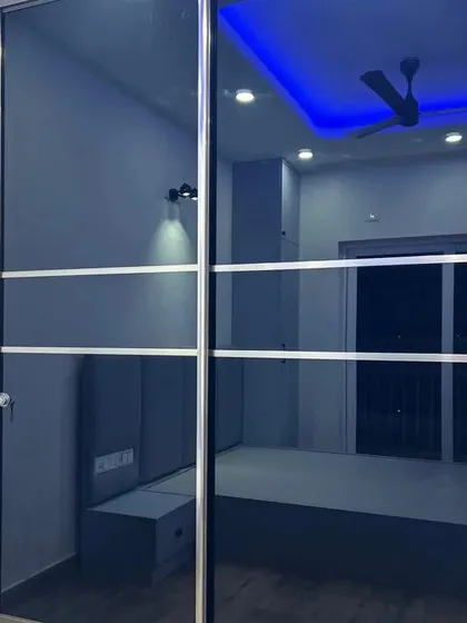 A sleek sliding wardrobe with black lacquered glass doors. This minimalist design is perfect for modern bedrooms, and the reflective surface helps to make the room feel more spacious.
