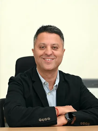 A clean and modern desk portrait. The simple background and direct gaze create a headshot that is focused, confident, and ready for any corporate platform.