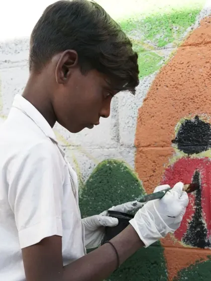 A close up of a student adding detail to a ladybug on the community wall. Every small contribution is a vital part of the larger story we create together. This is what makes public art projects so powerful.