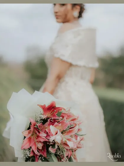 A beautiful focus-pull shot, with the bride's bouquet of lilies in the foreground and her elegant silhouette softly blurred behind.