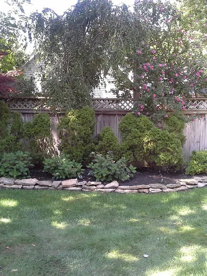 Here’s a look at a finished garden bed with a stacked stone border. Keeping the shrubs trimmed and the mulch fresh makes a yard look well cared for all year.