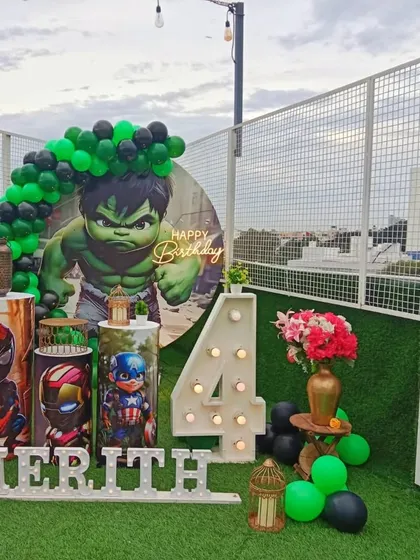 An epic superhero party on a rooftop terrace. This Avengers-themed setup features a massive Hulk backdrop, character-wrapped pedestals with Spider-Man and Captain America, and a light-up number 4.
