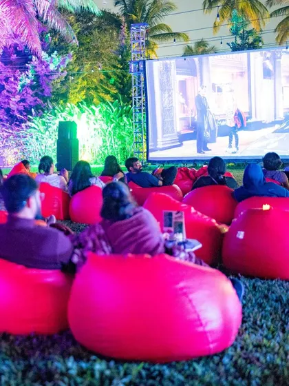 A wide shot of our open-air cinema setup, with guests relaxing on beanbags under the purple-lit palm trees.