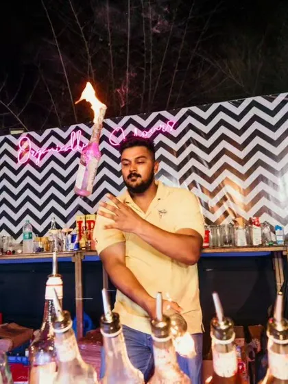 A bartender performs a shoulder roll with a flaming bottle, a classic flair move that always captivates the audience.