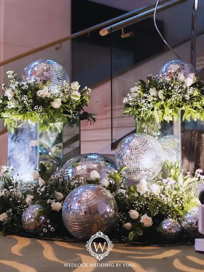 A walkthrough of a sangeet with an enchanted forest theme. The decor features a ceiling of lush greenery, sparkling disco balls, and glowing LED butterflies, creating a truly magical atmosphere.