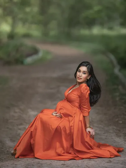 A duplicate of ID 24, this beautiful solo maternity portrait shows a mother-to-be in a stunning orange gown, seated on a rustic path and looking gracefully at the camera.