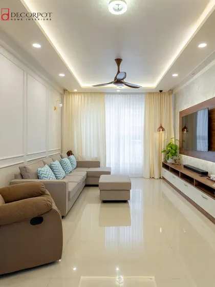 A bright and airy living room with a Scandinavian feel. The neutral sofa, light-colored walls with simple molding, and sheer curtains create a serene and calming atmosphere.