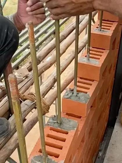 A close-up of the construction process, showing our skilled craftsmen carefully placing each perforated brick along the guide rods.