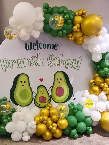 A fun and quirky avocado-themed welcome for baby Pransh Sehgal. The "avo-family" graphic on the backdrop is a playful and personalized touch for the new family of three.