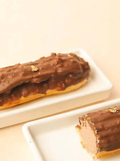 A close-up of our Rocher eclair, filled with a rich hazelnut cream and coated in chocolate with crunchy nuts.