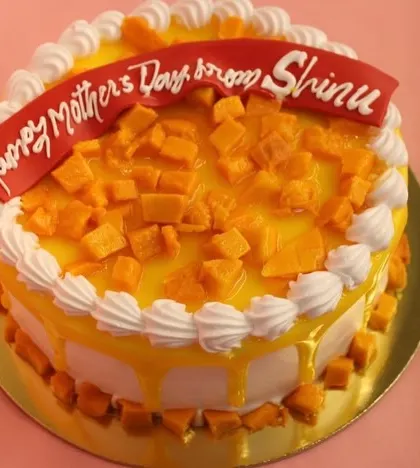 A special Mango Cake for a Mother's Day celebration, topped with fresh mangoes and a "Happy Mother's Day" banner.