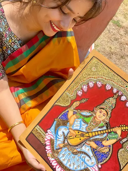 A detailed shot showing the intricate gold work and delicate features of the Saraswati painting.