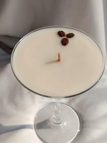 An elegant martini glass candle with layers of coffee-colored wax, topped with three coffee beans.