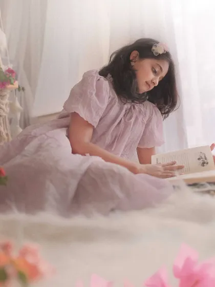 Another angle from the reading session, this portrait has a soft, dreamy quality. The light filtering through the curtains creates a magical, painterly effect.