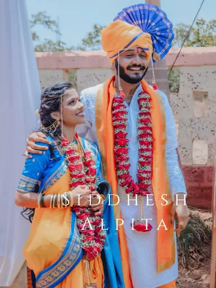 A happy portrait of a Maharashtrian couple, Siddhesh and Alpita, on their wedding day, showcasing their vibrant traditional outfits.