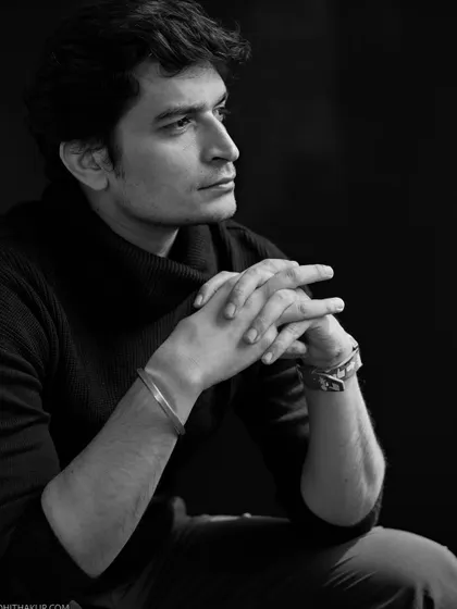 A thoughtful black and white portrait. The clasped hands and gaze into the distance create a pensive and intellectual mood, adding depth to an actor's portfolio.