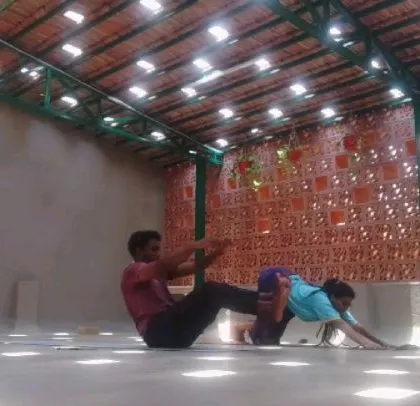 An instructor and student moving through the Ashtanga primary series. Here, we're working on Navasana (Boat Pose) and Downward-Facing Dog.
