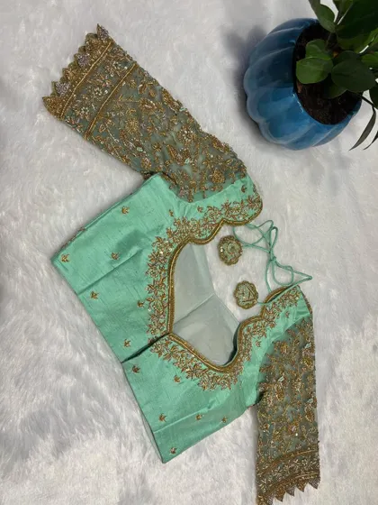 The back of the pastel green blouse, featuring an elegant cutout and intricate embroidery.