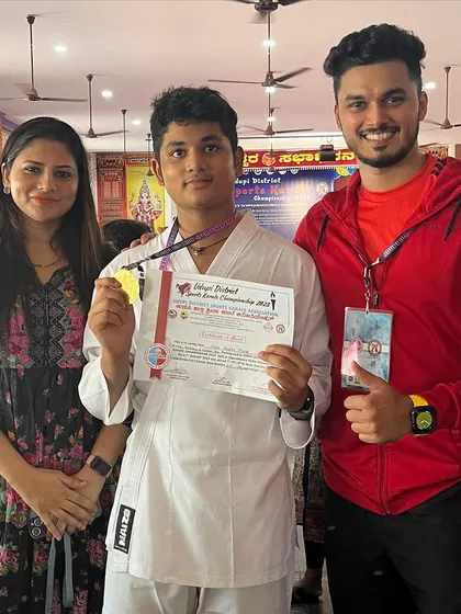 Proud parents and a proud coach. A student displays his gold medal from the Udupi District Sports Karate Championship.