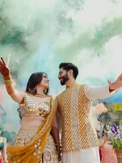 The couple makes a grand entry with colorful smoke bombs, adding a burst of energy and drama to their Mehndi celebration.