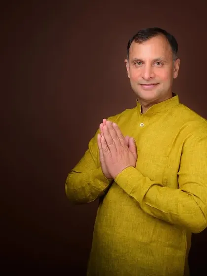A politician's portrait with a 'namaste' gesture against a warm background. This pose is welcoming and culturally resonant, perfect for connecting with constituents.